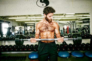 mixed race man lifting barbell in gymnasium
