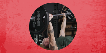 Individual performing a bench press in a gym setting.