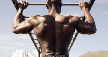 rearview shot of a muscular young man working out at a calisthenics park
