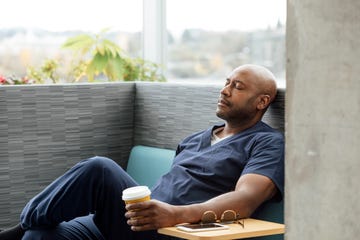 coffee and brain health: male health professional closing his eyes while sitting on the sofa with a coffee