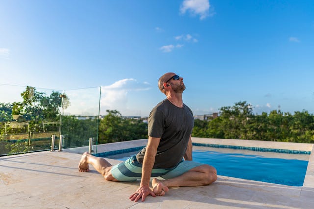 man practices yoga at poolside, while on holiday