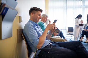patients sitting in waiting room using mobile phone