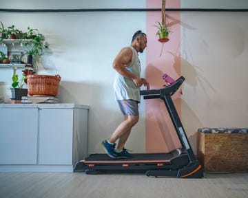 profile shot of a bearded matured man running on a treadmill at home