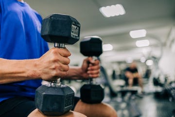 unrecognizable middle aged man works out hard with dumbbells in the gym