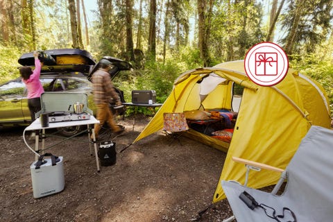Camping scene with gear setup next to a yellow tent in a forest area. Camping scene with gear setup next to a yellow tent in a forest area.