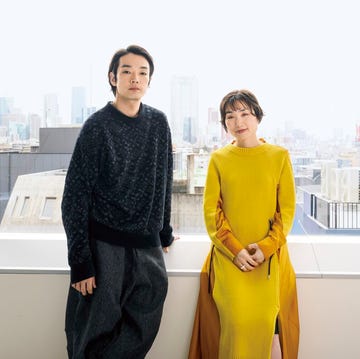 two individuals standing in front of a large window with a cityscape view two individuals standing in front of a large window with a cityscape view