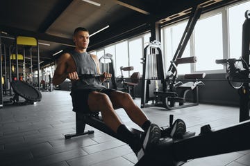 Athletic young man working out on rowing machine at fitness center athletic young man working out on rowing machine at fitness center
