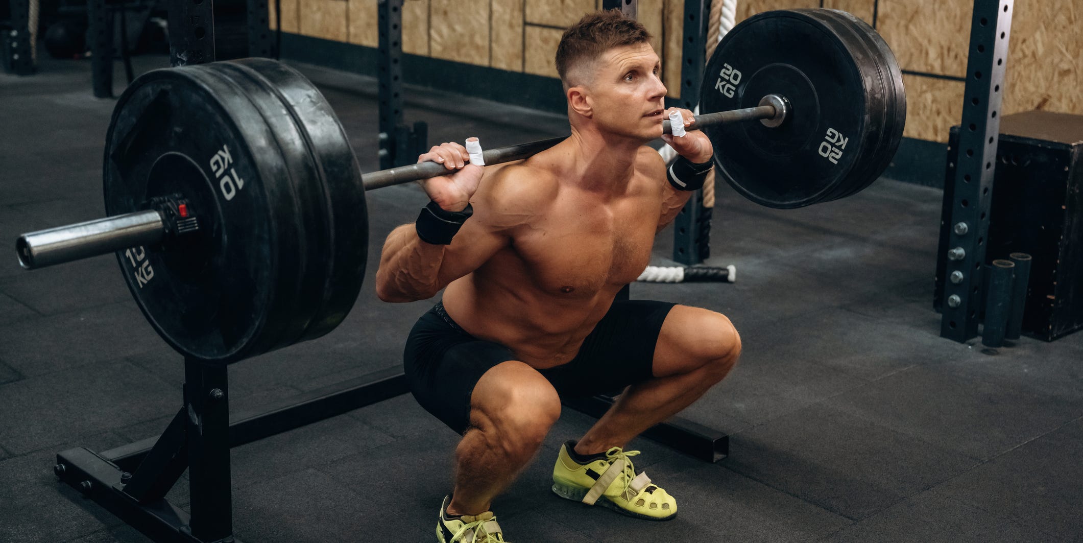 Sitting, ready for squats. Athletic man performing weightlifting exercises with a barbell in a gym sitting, ready for squats. athletic man performing weightlifting exercises with a barbell in a gym.