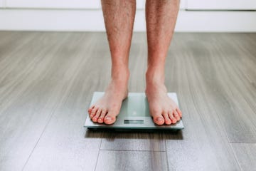 Checking his weight on the electronic weighing scale checking his weight on the electronic weighing scale
