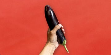 hand holding an eggplant to illustrate masturbation hand holding an eggplant against a red background