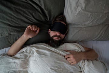 High angle view of man wearing sleep mask while sleeping on bed at home high angle view of man wearing sleep mask while sleeping on bed at home