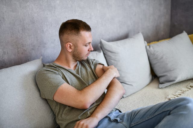 Male Picking At Scab With Fingers While Sitting On Couch male picking at scab with fingers while sitting on couch