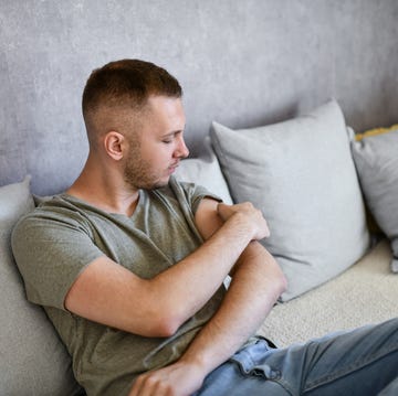 Male Picking At Scab With Fingers While Sitting On Couch male picking at scab with fingers while sitting on couch