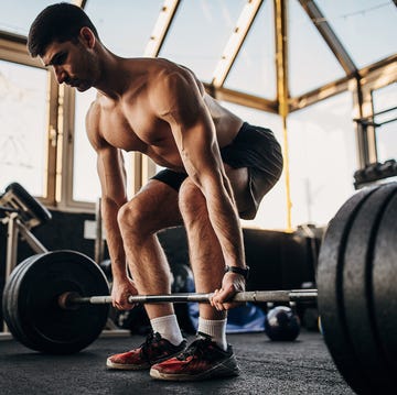 Muscular shirtless man exercising with weights in gym muscular shirtless man exercising with weights in gym