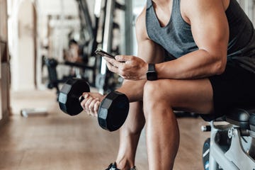 Muscular Young Man Training At Gym With Smart Phone muscular young man training at gym with smart phone