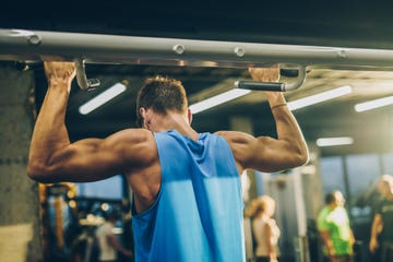 Rear view of muscular build man doing strength exercises in a gym. rear view of muscular build man doing strength exercises in a gym