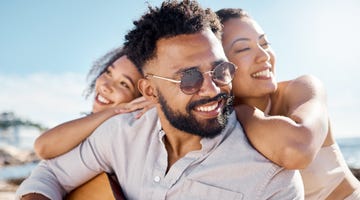 Shot of a man at the beach with his two female friends shot of a man at the beach with his two female friends