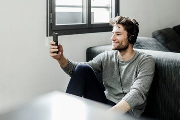 Smiling young man with cell phone and headphones at home Smiling young man with cell phone and headphones at home