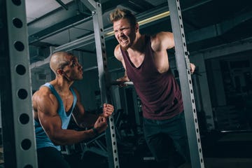 Two friends exercising dips at power rack in gym two friends exercising dips at power rack in gym