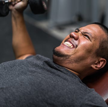 Young Asian man working out his chest muscle by using dumbbell young asian man working out his chest muscle by using dumbbell
