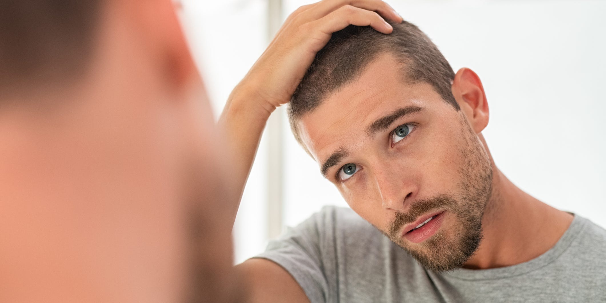 Young man checking hair in mirror Young man checking hair in mirror